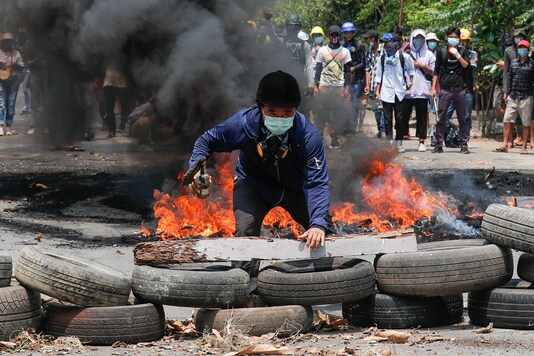 A man stands behind a barricade during a protest against the military coup, in Yangon, Myanmar on March 27. (Reuters)