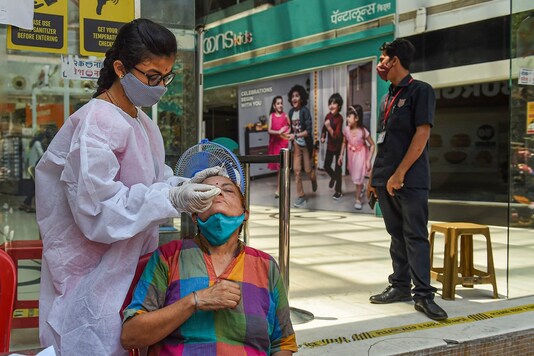 A health worker wearing protective gear takes swab sample of a visitor for COVID-19 tests, at a mall in Mumbai, Tuesday, March 30, 2021. (PTI)