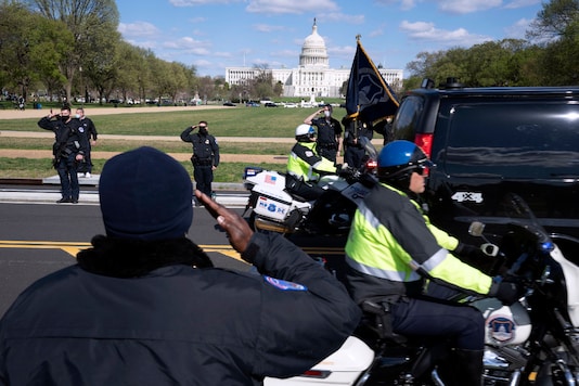 US Capitol Police officers salute as procession carries the remains of a Capitol Police officer who was killed after a man rammed a car into two officers at a barricade outside the Capitol in Washington, Friday, April 2, 2021. (AP Photo)