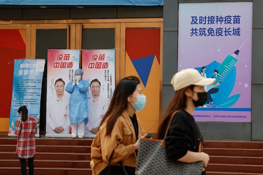 A medical worker stands near billboards portraying renowned Chinese Dr. Zhong Nanshan with the words "Vaccine China Made" at a vaccination site in Beijing on Friday, April 9, 2021. ​(AP Photo)