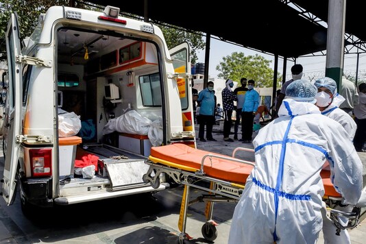 Health workers carry the body of a person who died of COVID-19 for cremation in New Delhi. (PTI)