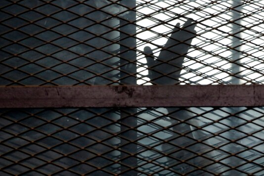 n this Aug. 22, 2015, file photo, a member of the Muslim Brotherhood waves his hand from a defendants cage in a courtroom in Torah prison, southern Cairo, Egypt. (AP Photo/Amr Nabil, File)