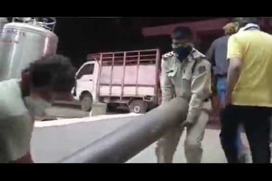 A cop is seen helping to lift oxygen cylinder at a hospital in Madhya Pradesh. 
