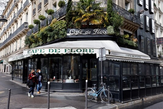 Women wearing protective face masks walk past the famous Cafe de Flore in Paris. (AFP)