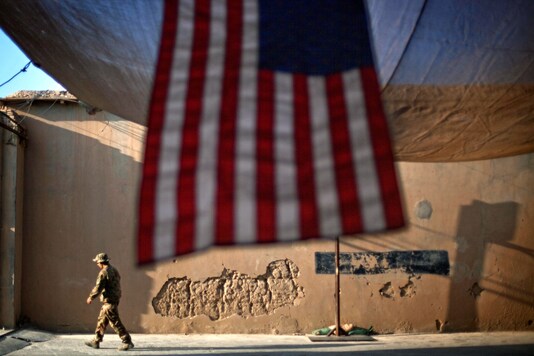 A US Army soldier walks past an American Flag hanging in preparation for a ceremony commemorating the tenth anniversary of the 9/11 attacks, at Forward Operating Base Bostick in Kunar province, Afghanistan. (AP Photo)