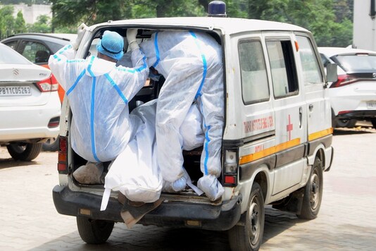 Health workers wearing PPE kits carry the body of a COVID-19 victim from a mortuary for cremation. (PTI)