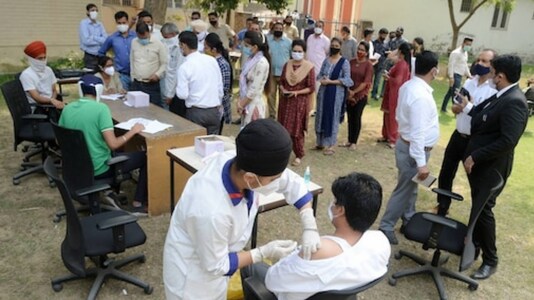 Health workers wearing PPE kits carry the body of a COVID-19 victim from a mortuary for cremation, in Patiala, Tuesday.