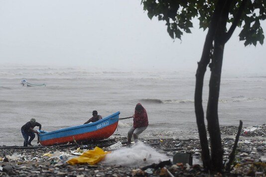 Fishermen pull their boat ashore to a safe place during formation of cyclone Tauktae, at Bandra in Mumbai, Monday. (PTI)