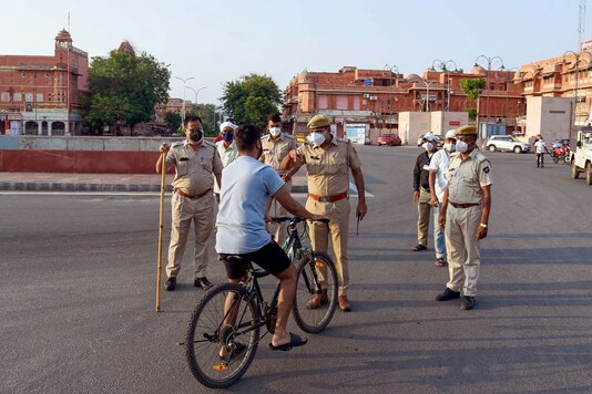 Police officers stop a cyclist for violating curfew norms. (PTI)