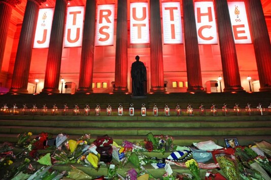 Flowers laid and candles are lit on the steps of St Georges Hall in Liverpool (Photo by PAUL ELLIS / AFP)