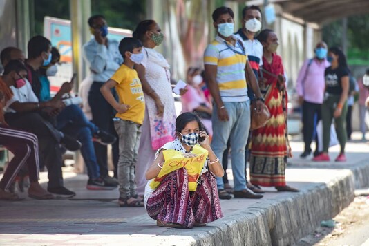 People, wearing face masks, wait for buses near Safdarjung hospital, in New Delhi, Thursday, May 27, 2021.  Delhi's positivity rate dropped below 2% for the first time in 60 days. (PTI)