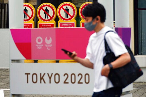 A man wearing a protective mask to help curb the spread of the coronavirus walks past a banner for the Tokyo 2020 Olympic and Paralympic Games on May 11, 2021, in Tokyo. (Image: AP)