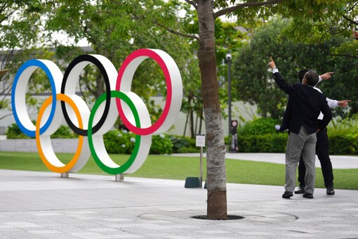 Men gestures near the Olympic Rings in Tokyo (AP Photo)