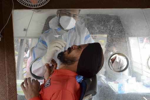 A health worker takes a nasal swab sample from a person for Covid-19 tests inside a mobile van. (Image: PTI)