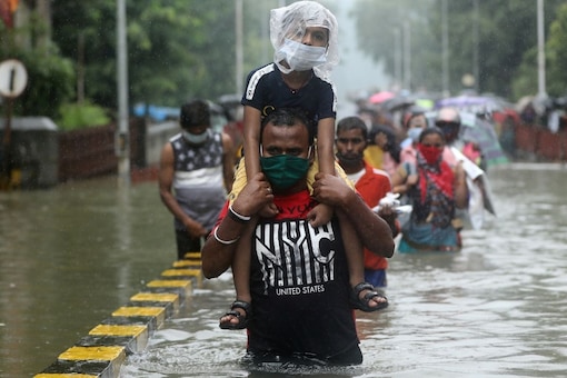 A man carries a child through a waterlogged road after heavy rainfall in Mumbai. Reuters 