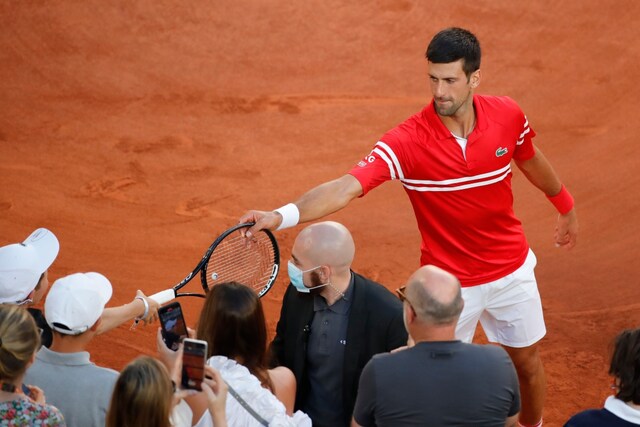 Novak Djokovic gives his match-winning racquet to a boy fan. (Photo Credit: Reuters)