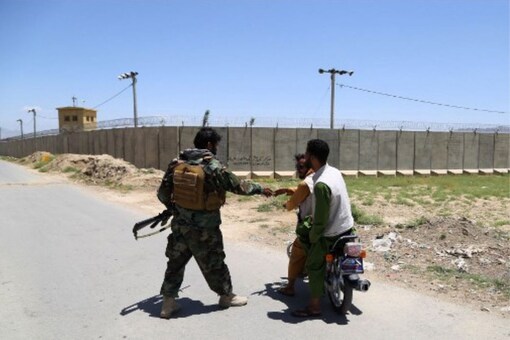 An Afghan National Army (ANA) soldier salutes locals riding on a motorbike outside Bagram Air Base, after all US and NATO troops left, some 70 Km north of Kabul on July 2, 2021.