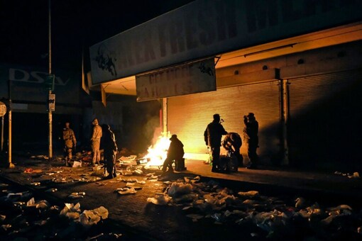 South African Defence Force soldiers keep themselves warm around a fire while stationed in Alexandra Township, near Johannesburg, to assist police in quelling looting and rioting. (AP)
