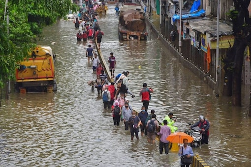 People wade through a waterlogged road in Mumbai. (PTI)