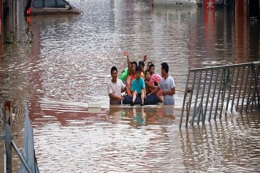 Children sit on a makeshift raft on a flooded road following heavy rainfall in Zhengzhou, Henan province, China. (Reuters)