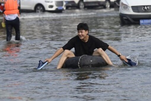 A resident moves with a swimming ring on a flooded road after heavy rain in Xinxiang, in central China’s Henan province on July 23, 2021. (Image AFP)