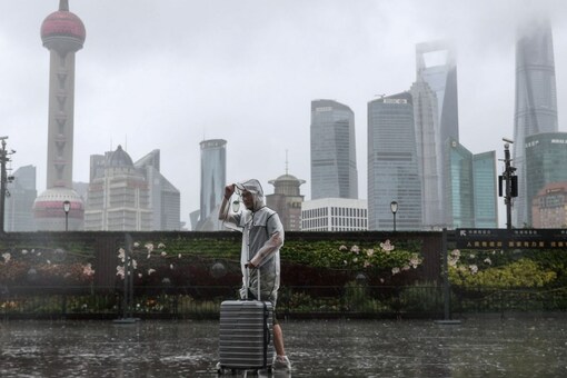 For File: A man with luggage walks in the rain on The Bund as Typhoon In-fa approaches Shanghai, China July 25, 2021. Via Reuters