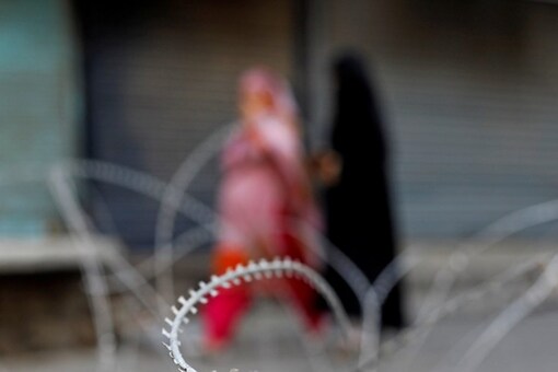 Kashmiri women walk through concertina wires laid across a road in Srinagar.  (Reuters)