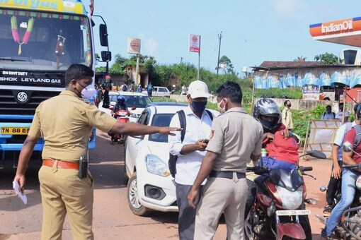 Police personnel check the COVID-19 test report of travellers at Talapady checkpost at Kerala-Karnataka border in Mangaluru. (PTI)