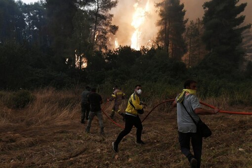 Firefighters and volunteers try to extinguish a wildfire burning in the village of Gouves, on the island of Evia, Greece, August 8, 2021. REUTERS/Alexandros Avramidis

