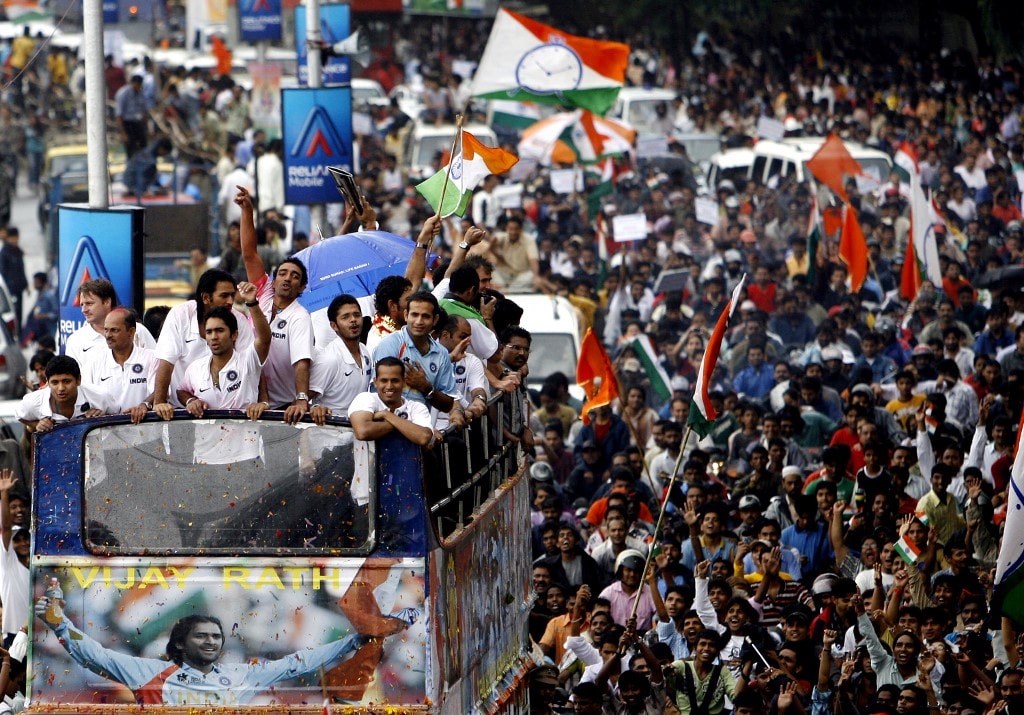 Members of India's cricket team greet crowds from atop an open topped bus at a special falicitatory function at the Wankhede stadium in Mumbai, 26 September 2007. Thousands thronged the streets, braving monsoon rain to greet the cricketing heroes who lifted the inaugural Twenty20 world title against Pakistan in Johannesburg. AFP PHOTO/ Sajjad HUSSAIN (Photo by SAJJAD HUSSAIN / AFP)