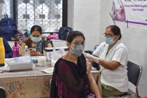 A medical worker (R) inoculates a woman with a dose of the Covishield vaccine against the Covid-19 coronavirus at a hospital in Allahabad on September 6, 2021. (Image: Sanjay KANOJIA/AFP)