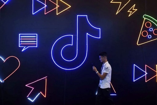 A man holding a phone walks past a sign of Chinese company ByteDance's app TikTok, known locally as Douyin. (Image: Reuters)