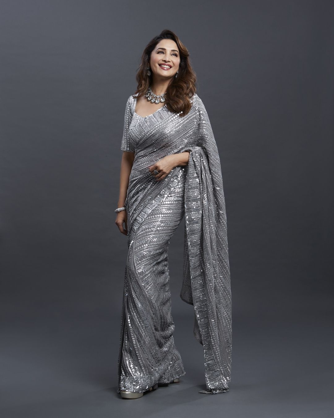 Madhuri Dixit looks chic in the shimmering silver saree. 