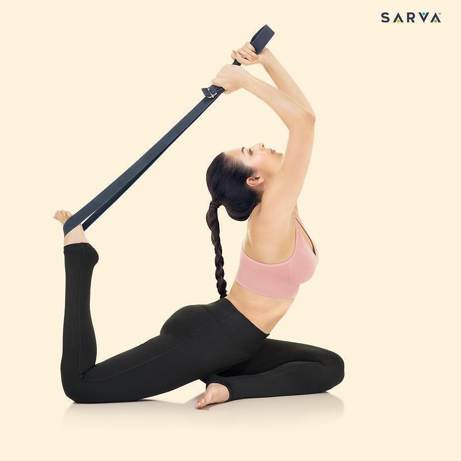 Malaika Arora stretches using a belt. 