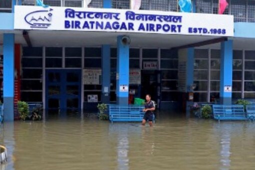 A man wades through the flooded entrance of a domestic airport at Biratnagar after heavy rains in Nepal. (Image: Lila Ballav Ghimire/AFP)
