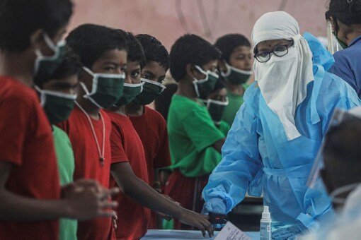 A health worker in personal protective equipment (PPE) checks the pulse of a child at a children's home. (Reuters)