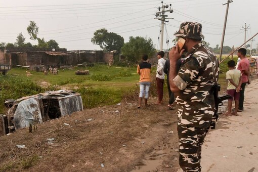 Lakhimpur Kheri Violence: A security officer stands guard as locals take a look at the overturned SUV at Tikonia area on October 4. (PTI Photo)