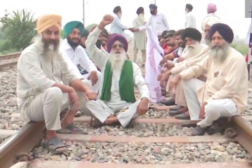 Farm law protestors sit on the railway track at Devi Dasspura village in Amritsar following farmer's union call for 'Rail Roko Andolan'. (Twitter/ANI)