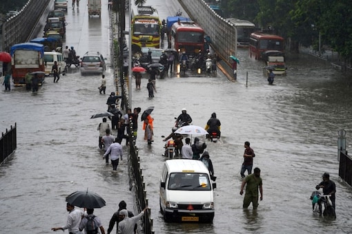 People wade through a waterlogged road after heavy rains in Mumbai. (Image: Reuters)
