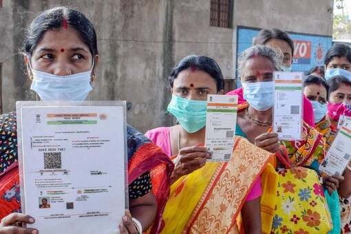 Beneficiaries hold up their Aadhaar cards as they wait in queue to receive a dose of Covid-19 vaccine, in West Bengal’s Nadia on December 2, 2021. (Representative image/PTI)