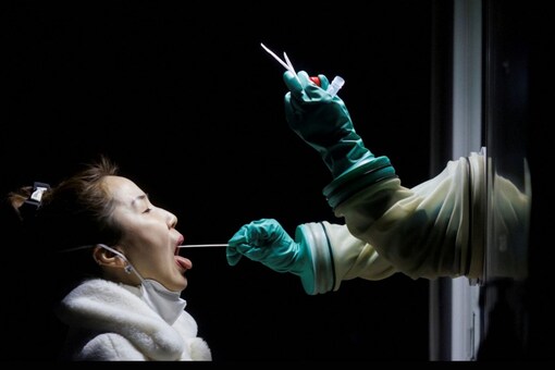 A woman receives a throat swab test at a street booth in China. (Image: Thomas Peter/Reuters)