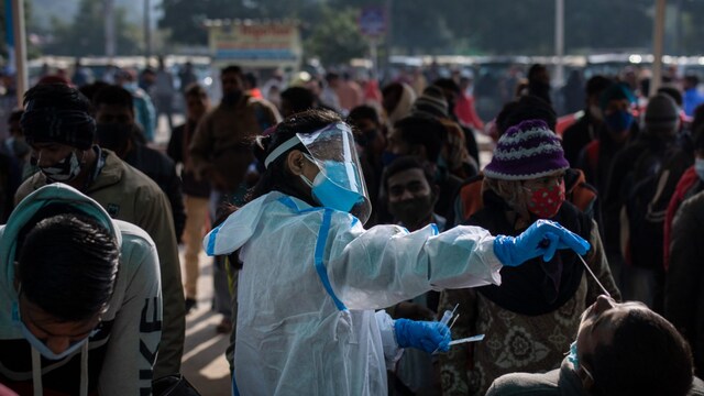 A health worker collects a swab sample of a passenger to test for Covid-19 as others wait for their turn at a train station in New Delhi, (AP Photo/Altaf Qadri)