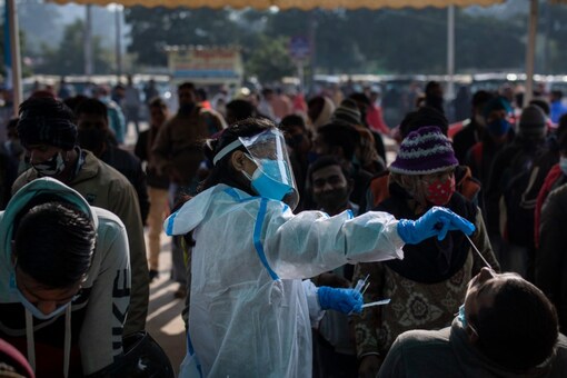 A health worker collects a swab sample of a passenger to test for Covid-19 as others wait for their turn at a train station in New Delhi, on December 30, 2021. (AP Photo/Altaf Qadri)