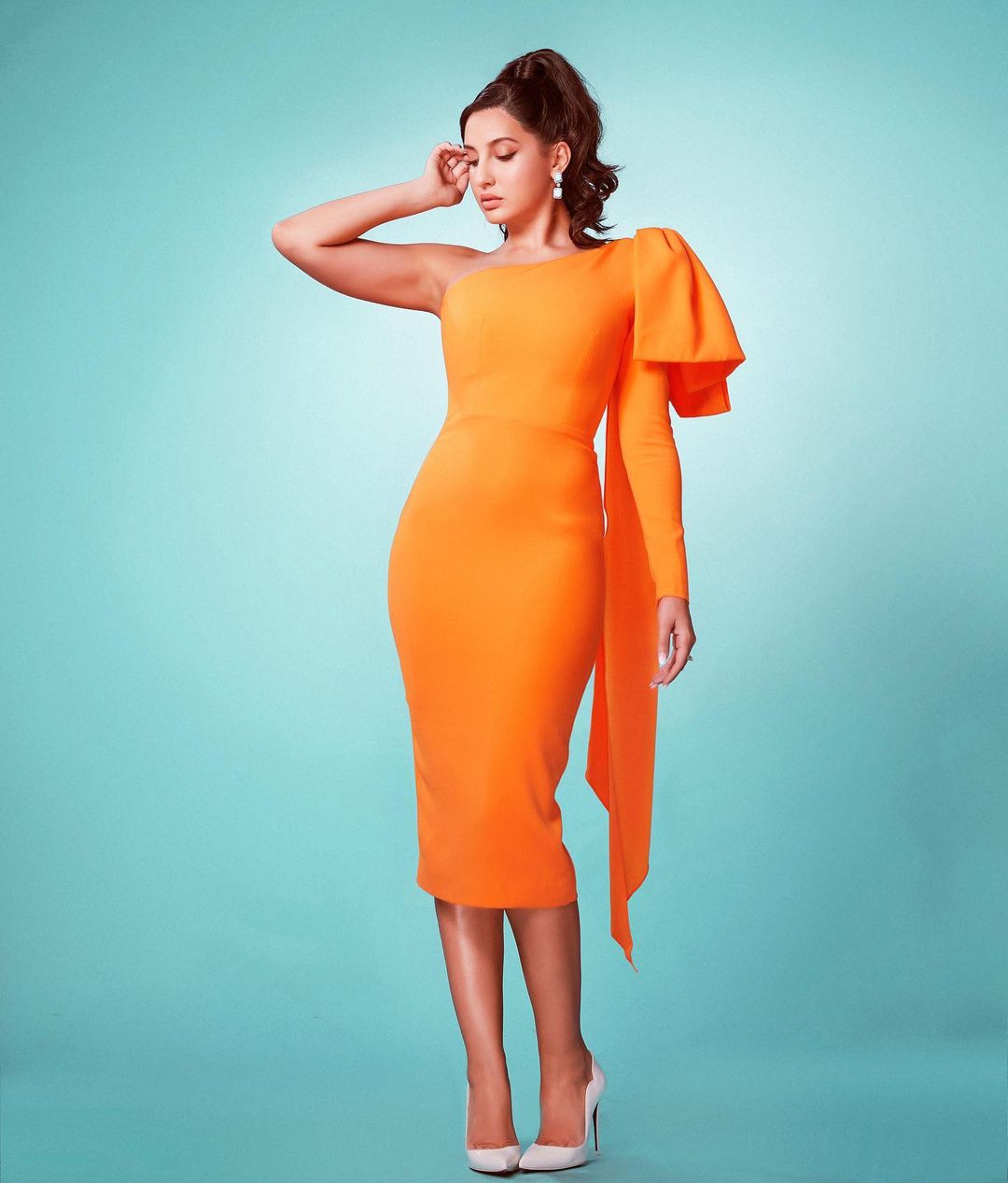 Nora Fatehi looks flawless in the asymmetrical orange dress. 