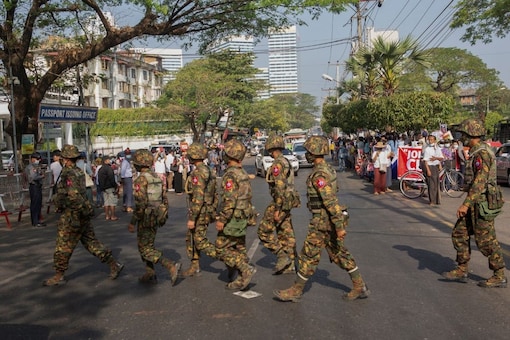 Soldiers cross a street as people gather to protest against the military coup, in Yangon, Myanmar, February 15, 2021. REUTERS/Stringer
