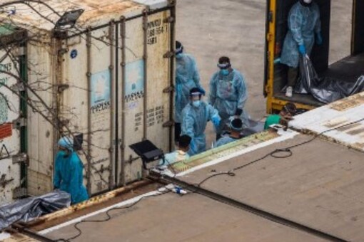 Workers move the bodies of deceased people from a truck into a refrigerated container at the Fu Shan Public Mortuary in Hong Kong on March 16. (Image: AFP)