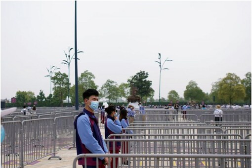 Staff members wearing face masks stand outside the Shanghai Disneyland theme park as it reopens following a shutdown due to Covid outbreak at Shanghai Disney Resort in Shanghai, China (Image: Reuters)
