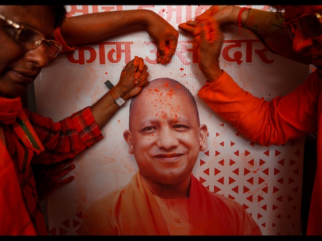BJP workers apply gulal on a photograph of Yogi Adityanath as they celebrate the party’s return to power in Uttar Pradesh, in Lucknow on March 10, 2022. (AP Photo/Rajesh Kumar Singh)