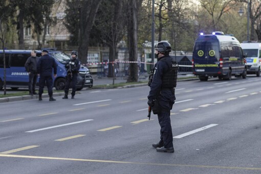 Police officers stand guard as crime scene investigators check the area where a car crashed into the gate of the Russian Embassy in Bucharest, Romania (Image and Caption: Reuters)