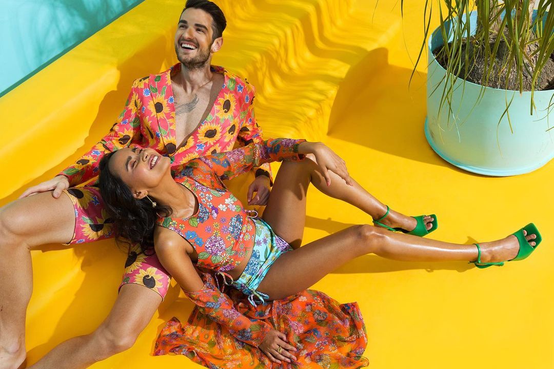 Models strike a pose in a coral sunflower printed full sleeve shirt with shorts and a tangy orange and turquoise printed reversible bikini designed by label Nautanky. Image: Instagram